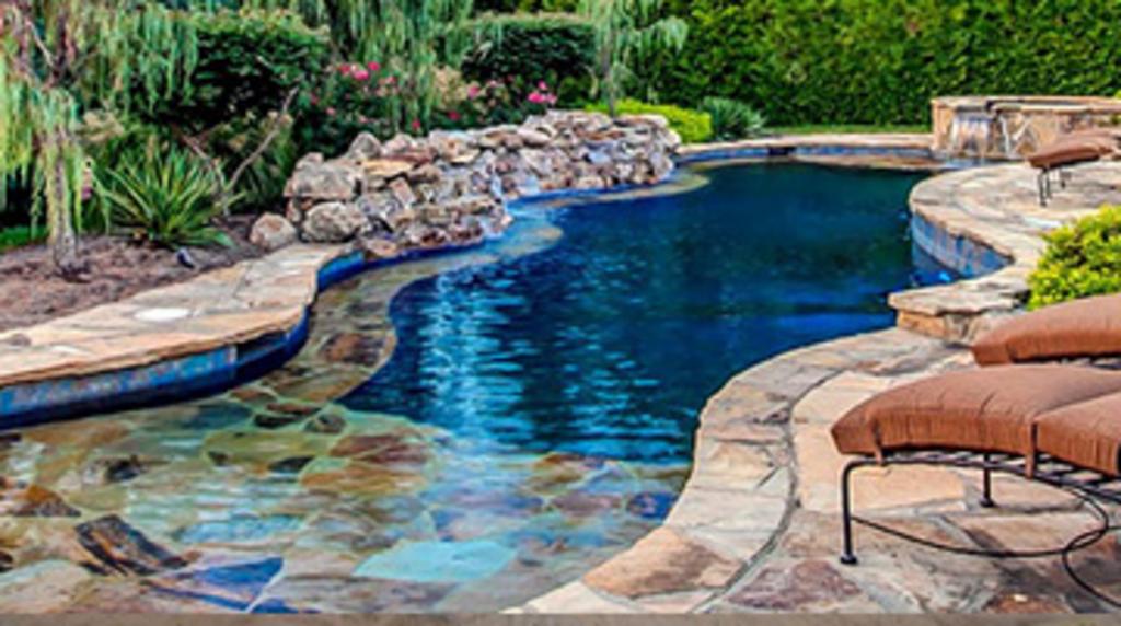 Stone tiled, wade in remodeled pool with jacuzzi and waterfall  