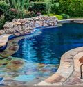 Stone tiled, wade in remodeled pool with jacuzzi and waterfall